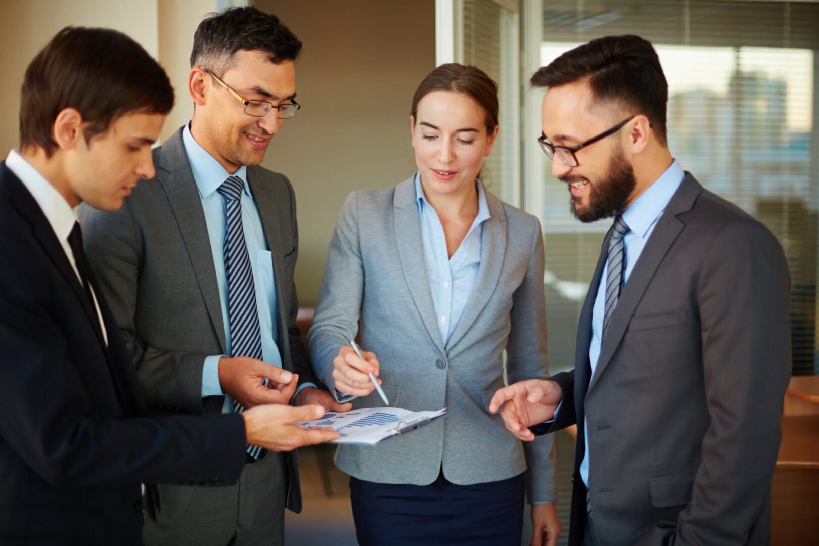 Confident businesswoman pointing at document while explaining data to her partners in office